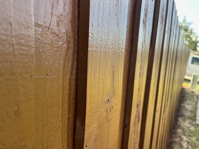 Close-up of a freshly stained wooden fence in a light brown color, angled perspective.