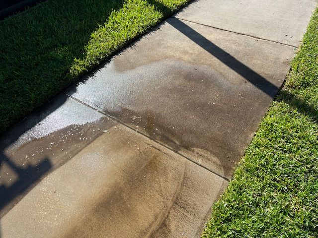 A person is using a high pressure washer to clean a sidewalk.