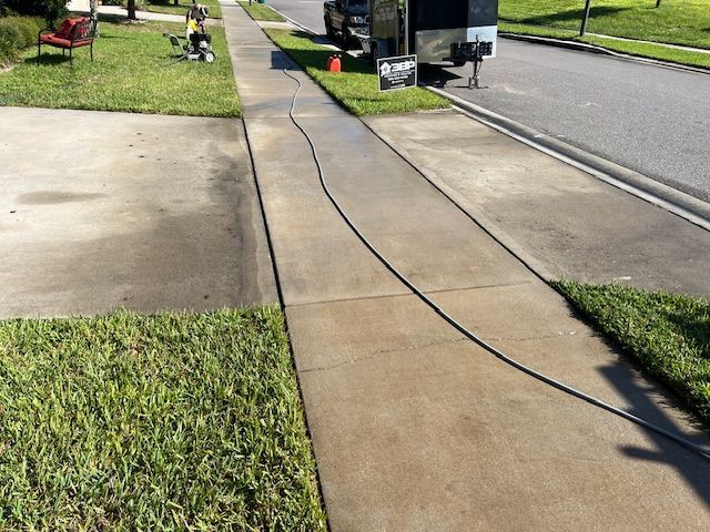 A person is cleaning a wooden roof with a high pressure washer.