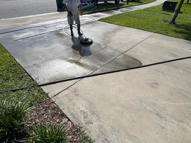 A person is cleaning the side of a house with a high pressure washer.