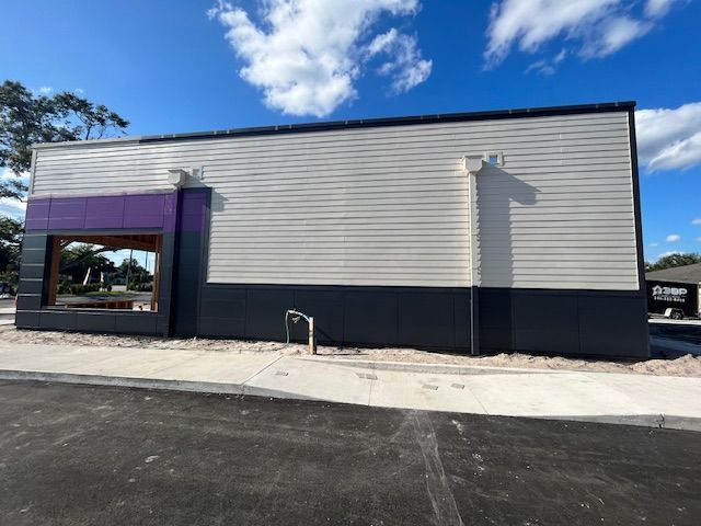 Exterior of a Taco Bell restaurant under construction with purple, white, and gray color scheme.