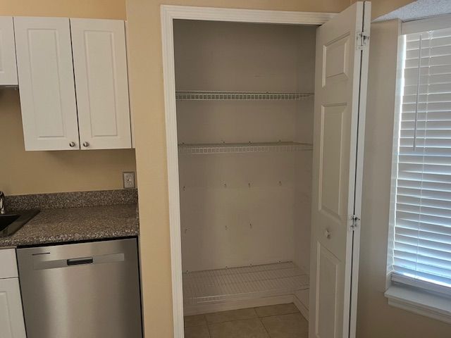 Open kitchen pantry with wire shelves, white doors, and sunlight through a window.