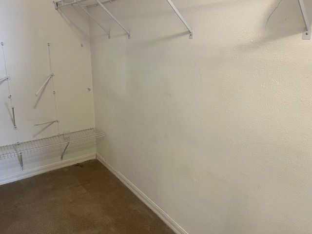 Empty white-walled closet with wire shelving and a brown carpeted floor.
