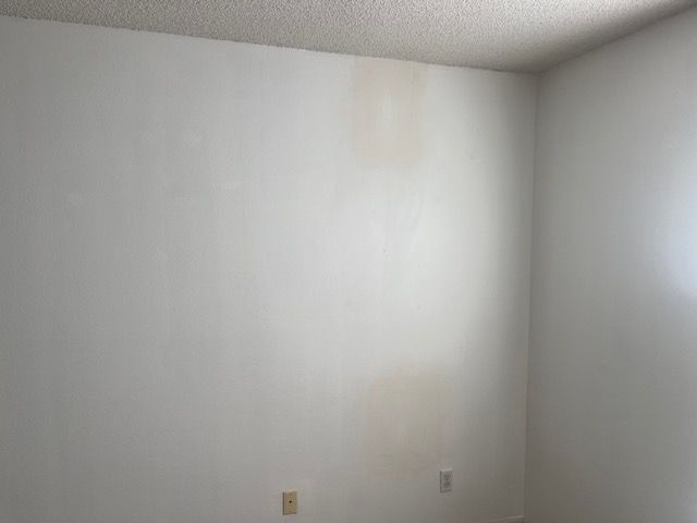 White walls with water stains and electrical outlets in a room.