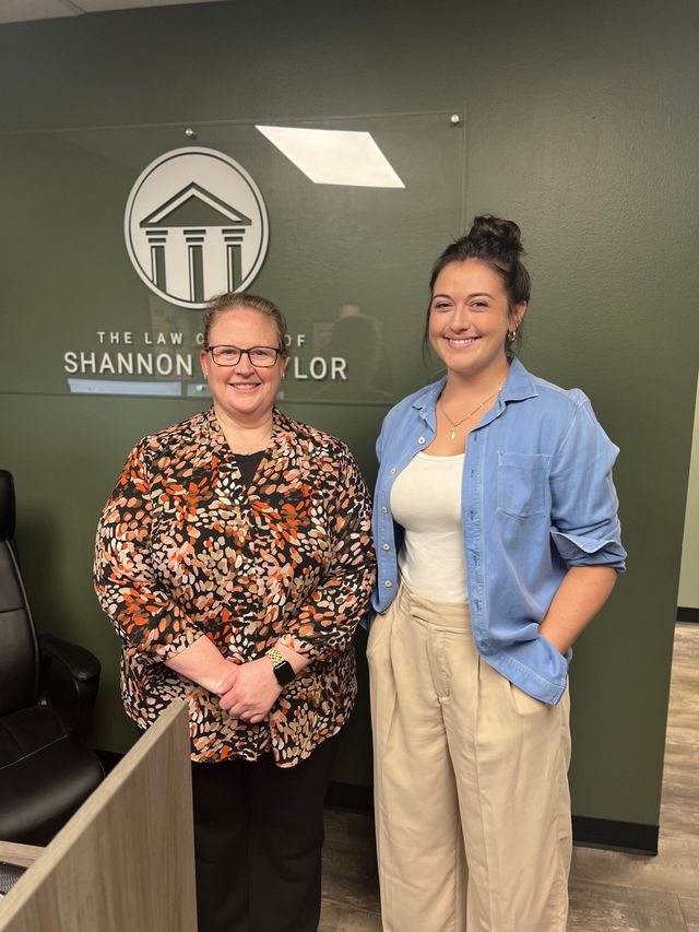 Two women standing in front of a sign that says shannon taylor