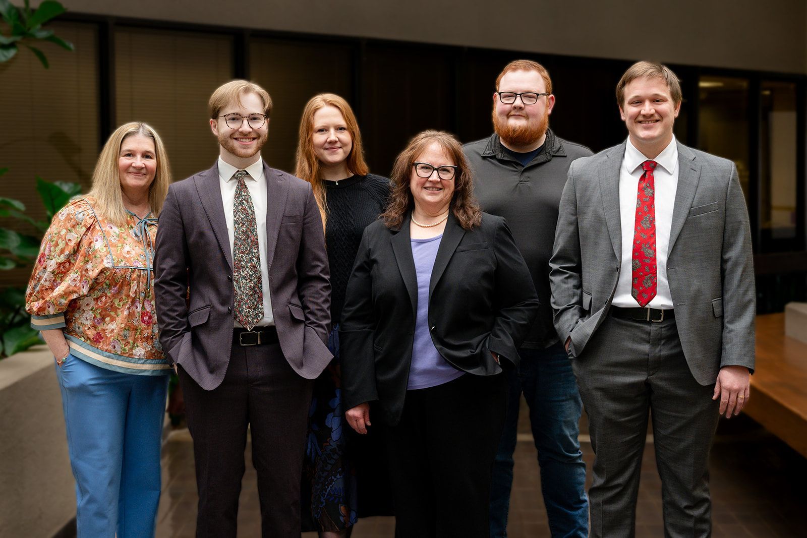 A judge is sitting at a desk in front of a bookshelf.