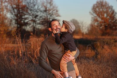 A man is holding a child in his arms and the child is kissing the man on the cheek.