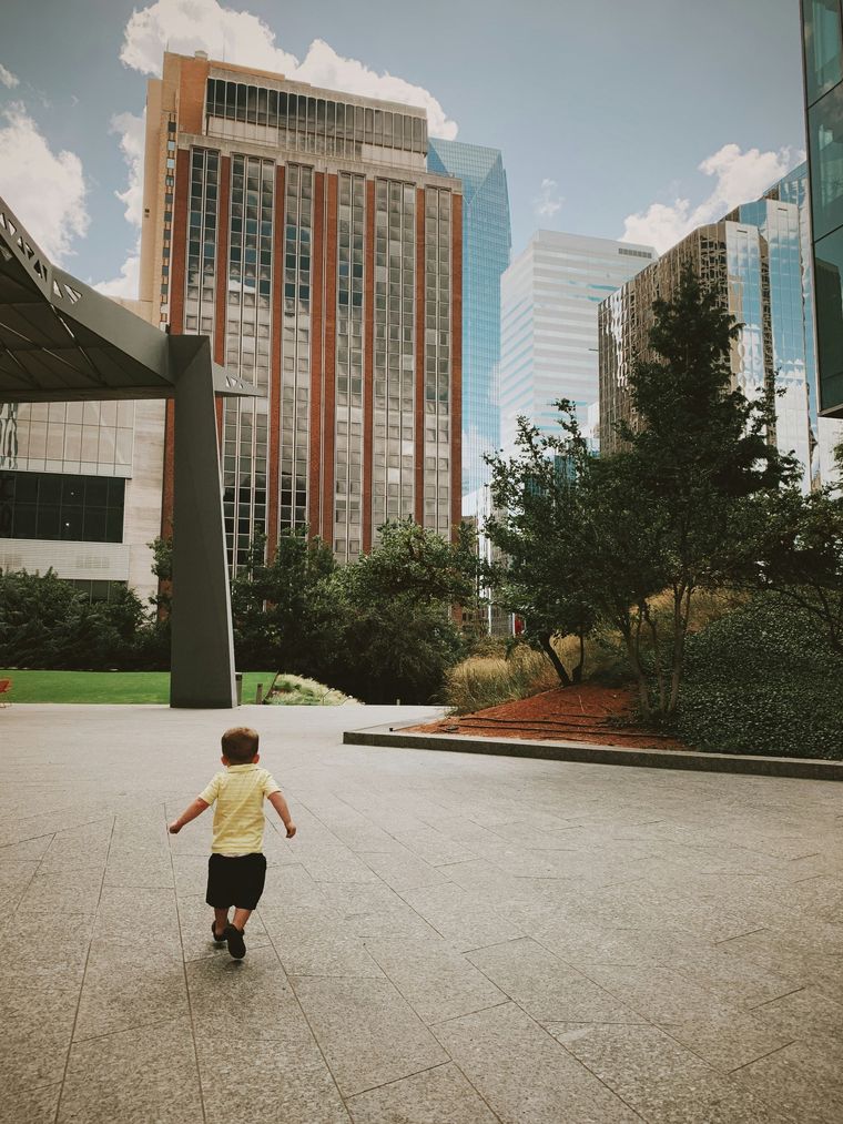 A little boy is running in front of a large building