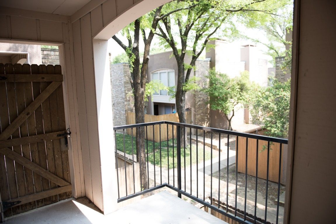 A balcony with a fence and trees in the background