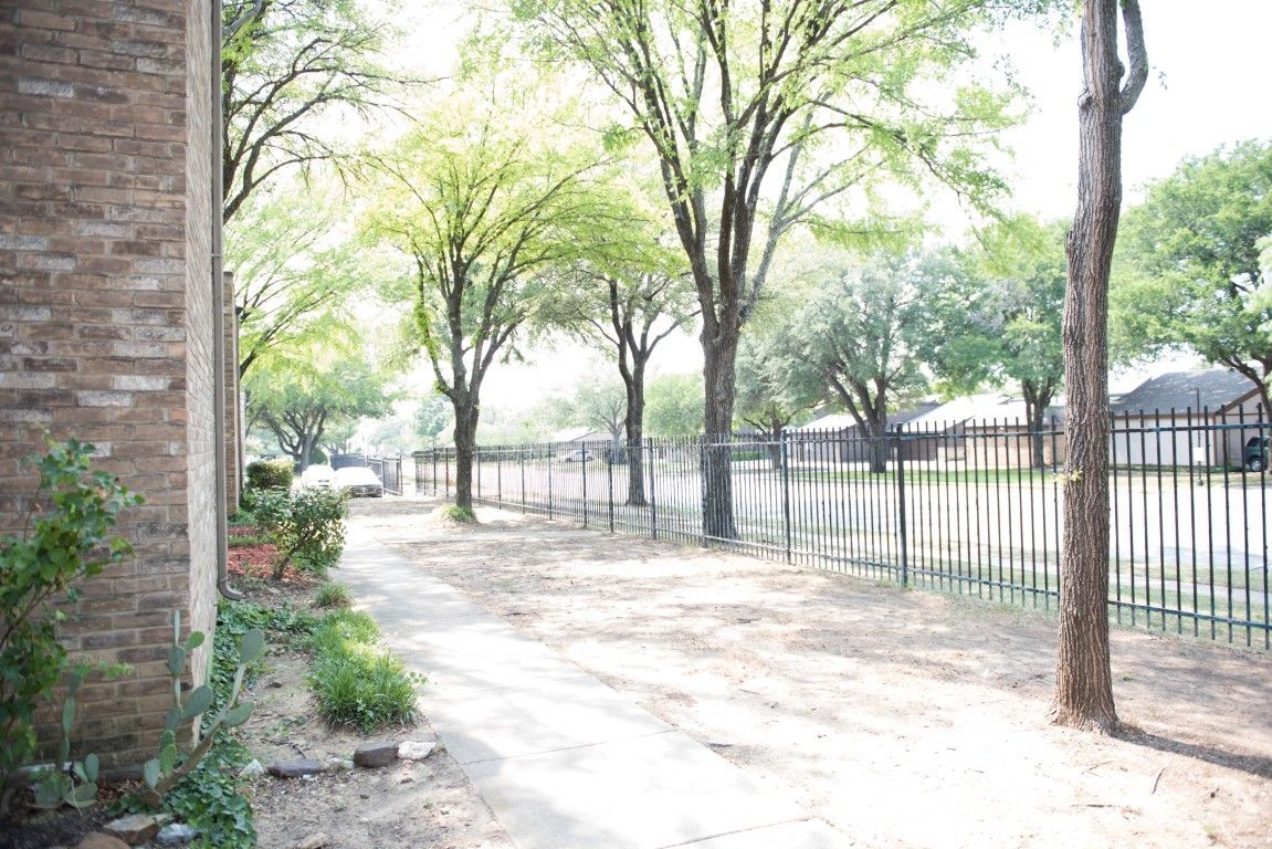 A brick building with a fence and trees in front of it.