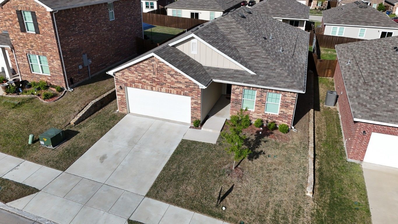 An aerial view of a brick house in a residential neighborhood.