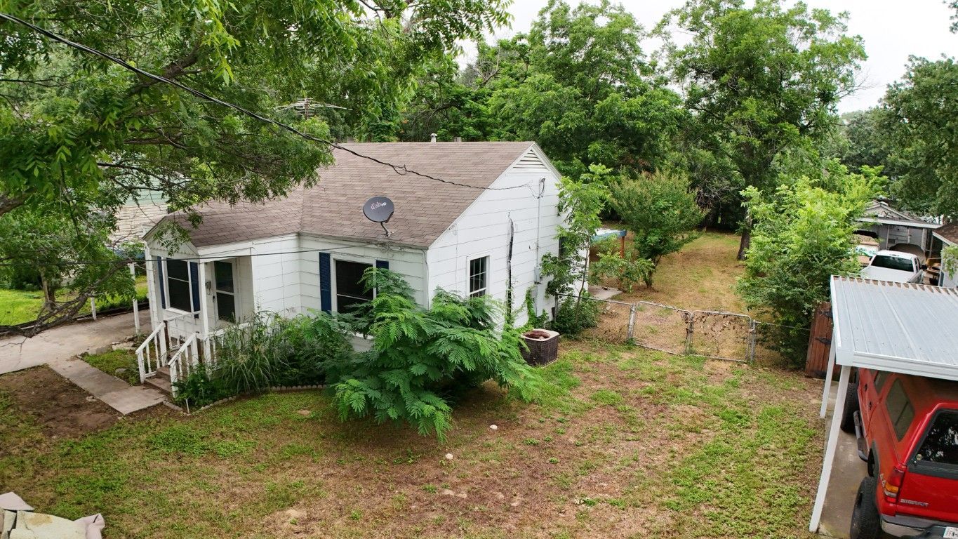 An aerial view of a small white house with a red truck parked in front of it.