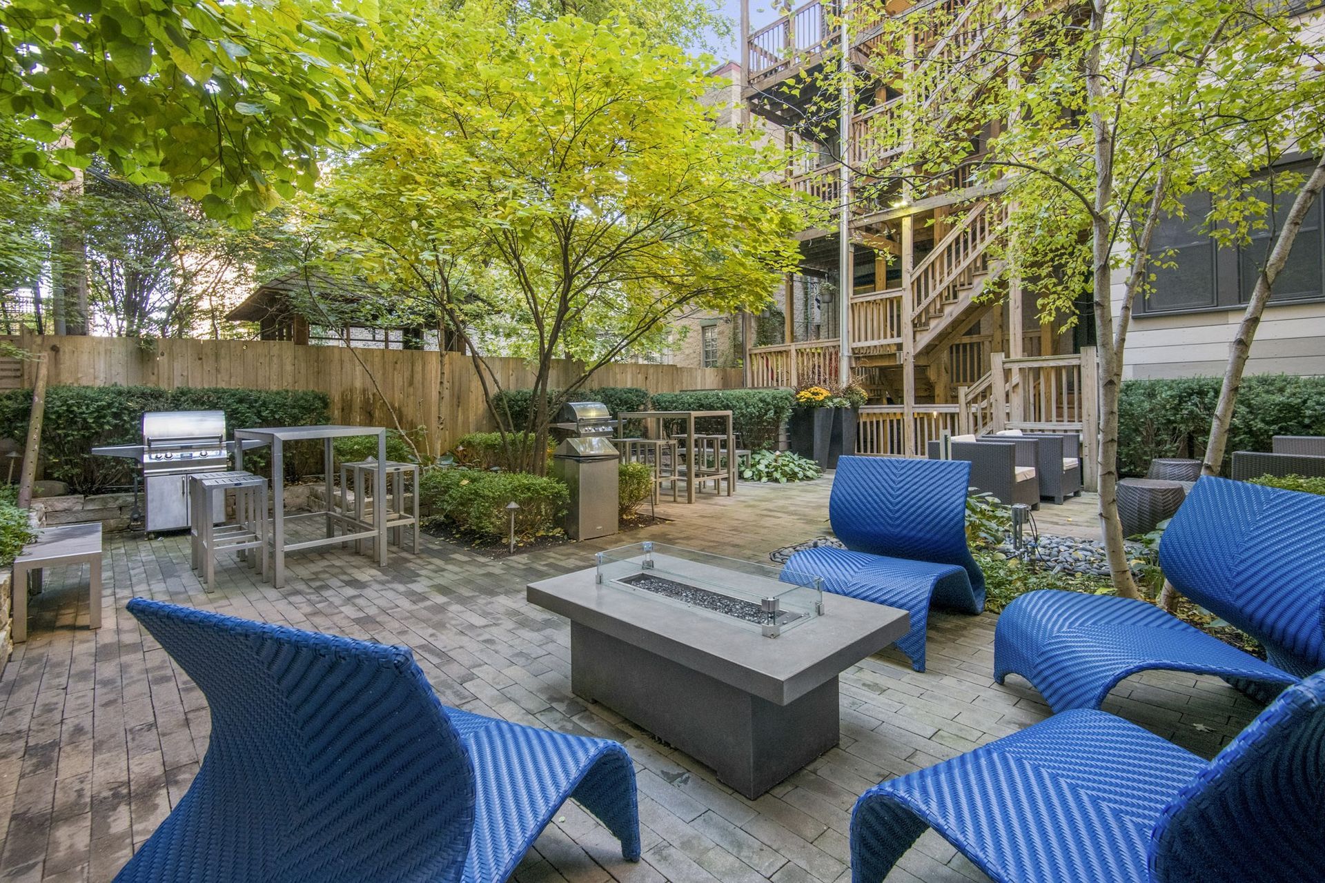 a patio with blue chairs and a fire pit