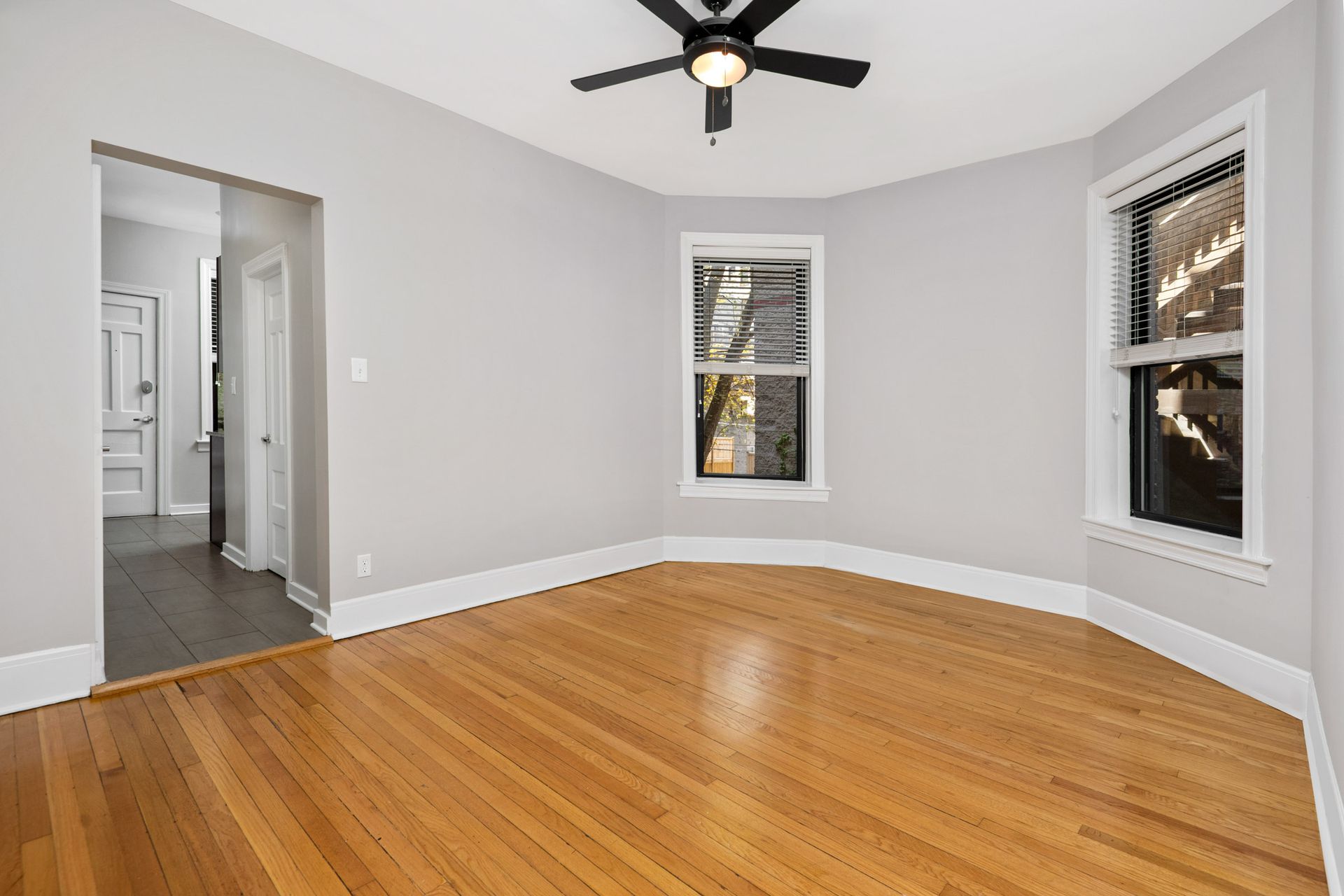 An empty living room with hardwood floors and a ceiling fan at 429 W Melrose Street.
