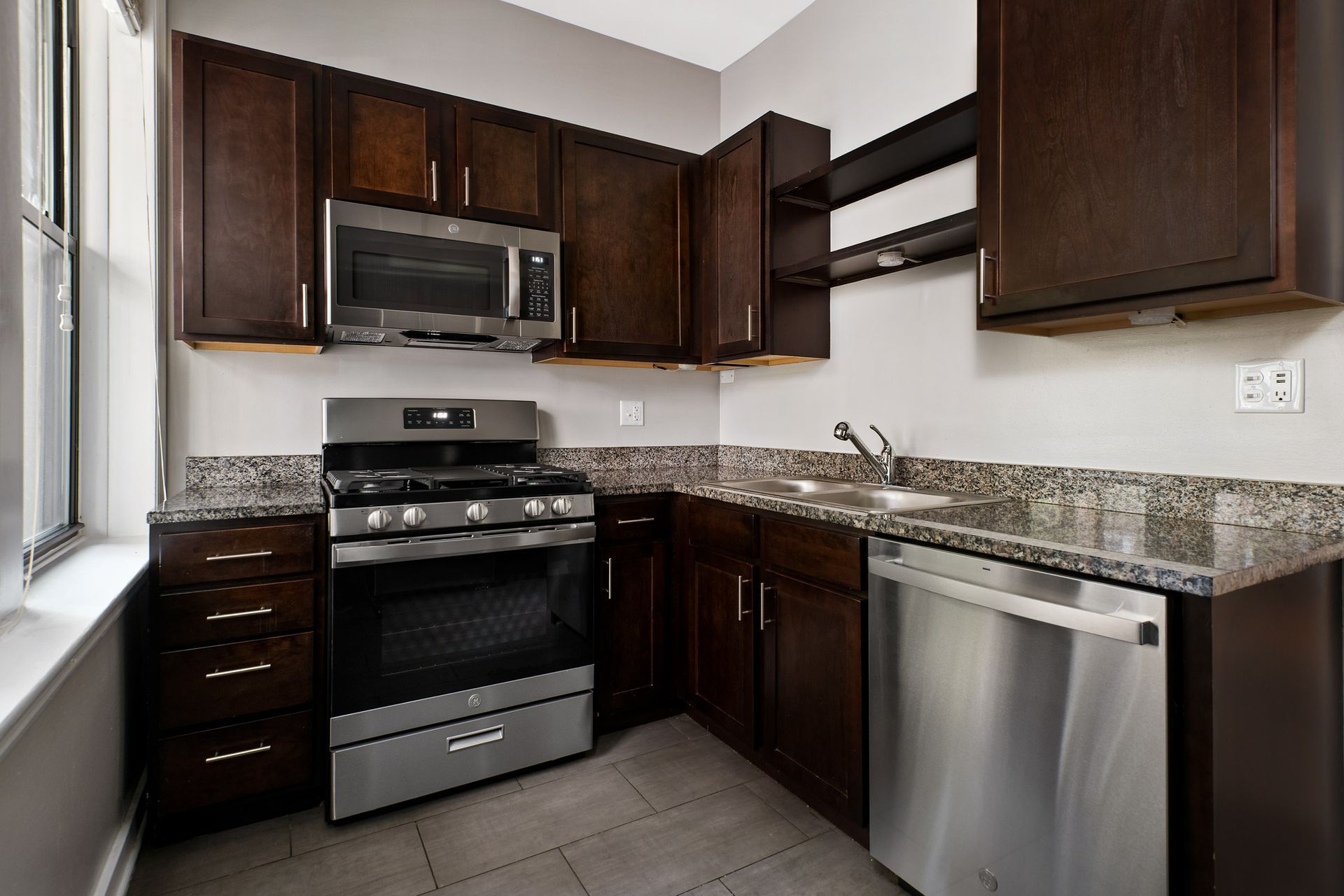 Apartment kitchen with stainless steel appliances and wooden cabinets at 429 W Melrose Street.