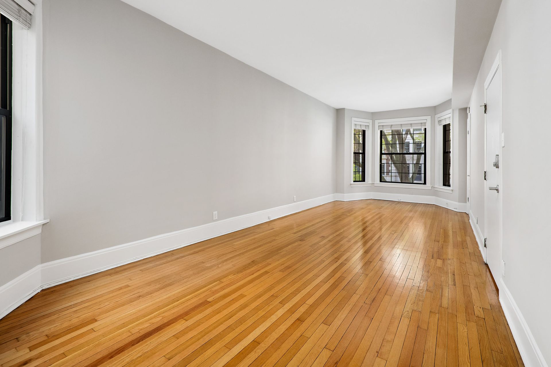 An empty living room with hardwood floors and white walls at 429 W Melrose Street.