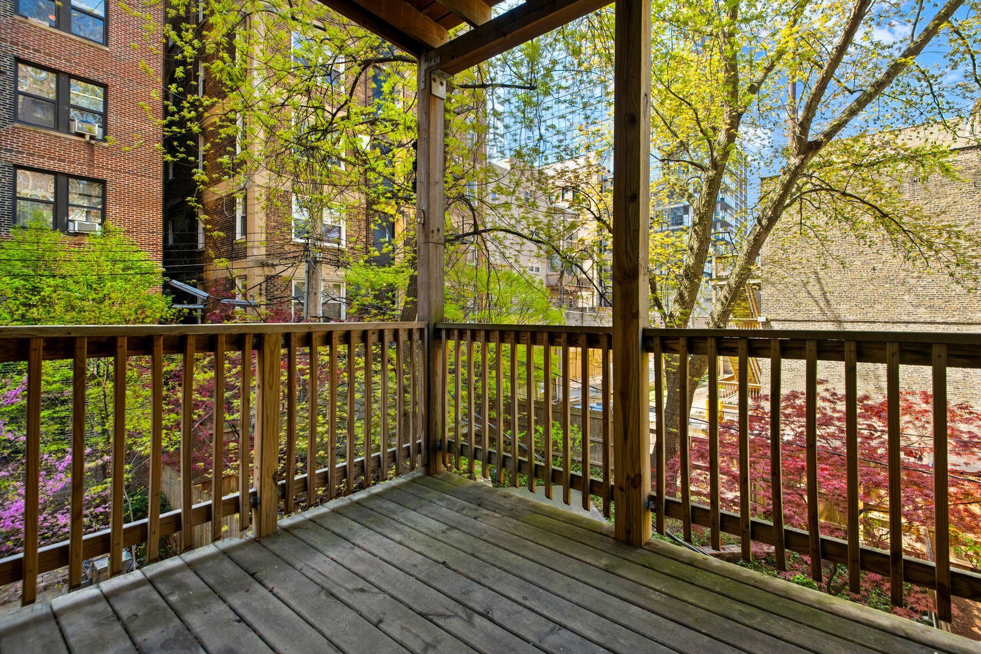 An empty porch with a wooden railing and trees in the background.