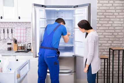 repairman fixing the freezer while lady looking at him