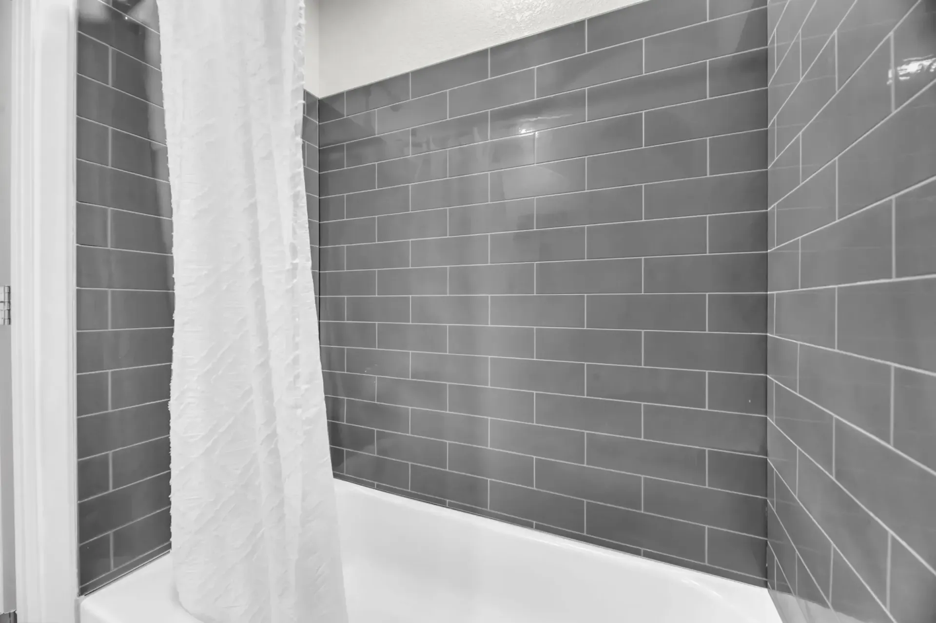 a bathroom with gray tiles and a white shower curtain