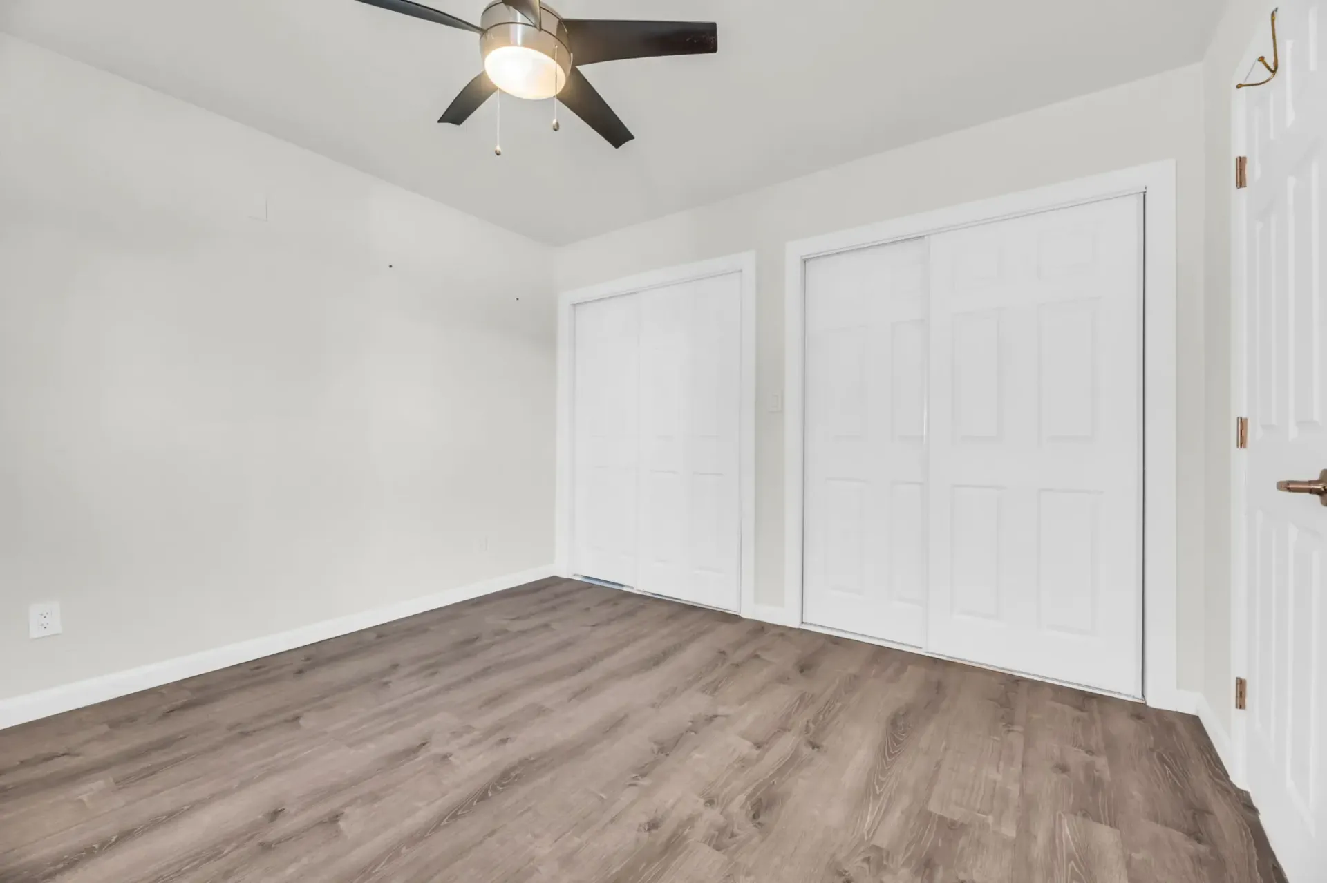 an empty room with a ceiling fan and sliding doors