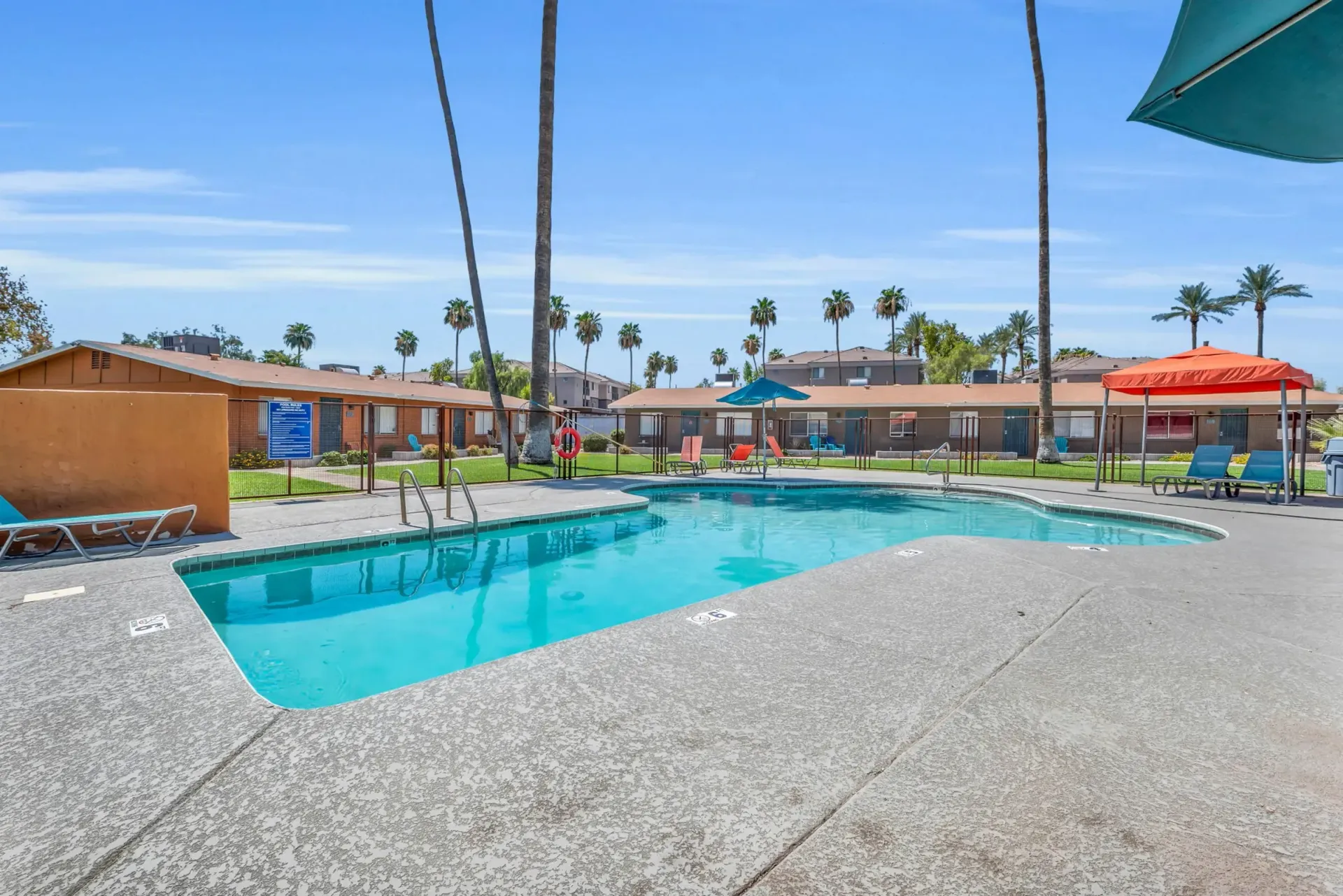a large swimming pool is surrounded by chairs and umbrellas