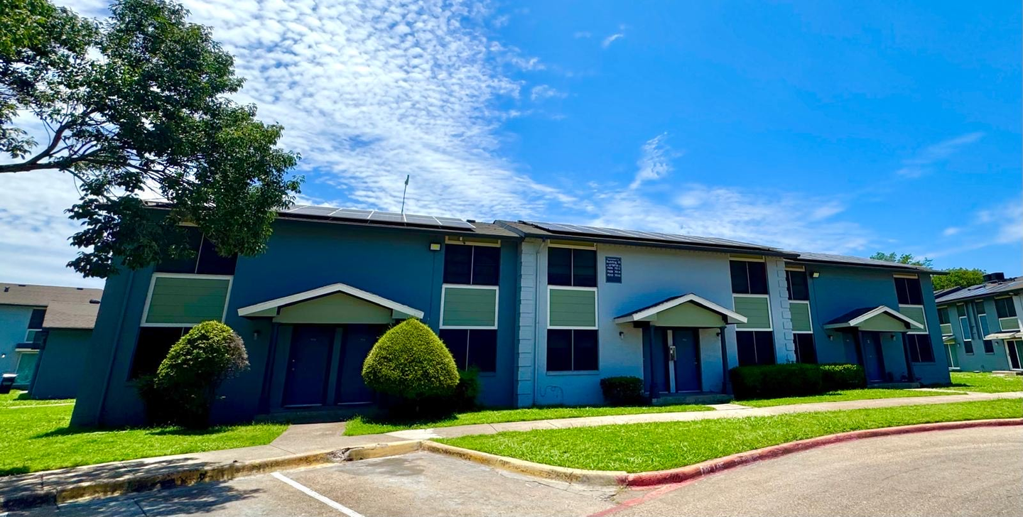 A blue and green apartment building with a blue sky in the background.