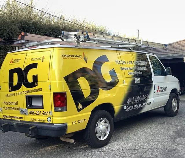 Woman holding baby, smiling, near staircase. Child watches from behind a table.