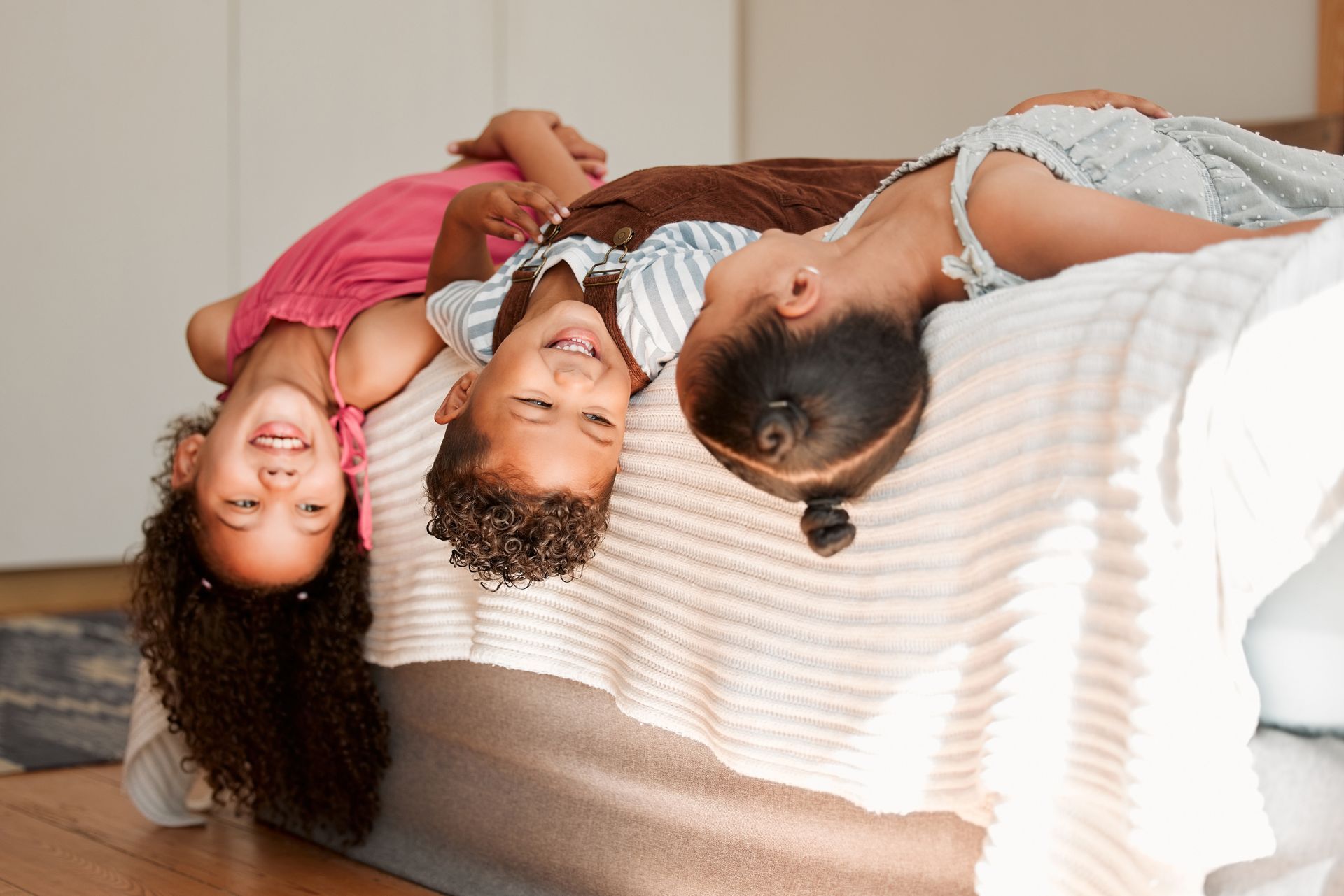 Woman holding baby, smiling, near staircase. Child watches from behind a table.