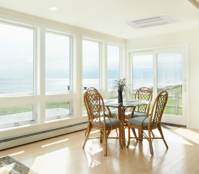 Woman holding baby, smiling, near staircase. Child watches from behind a table.