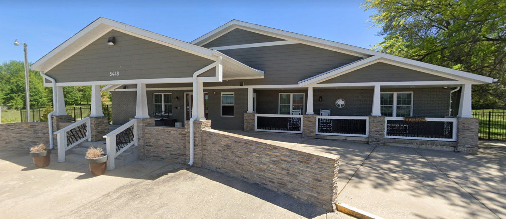 A large house with a large porch and a stone wall.