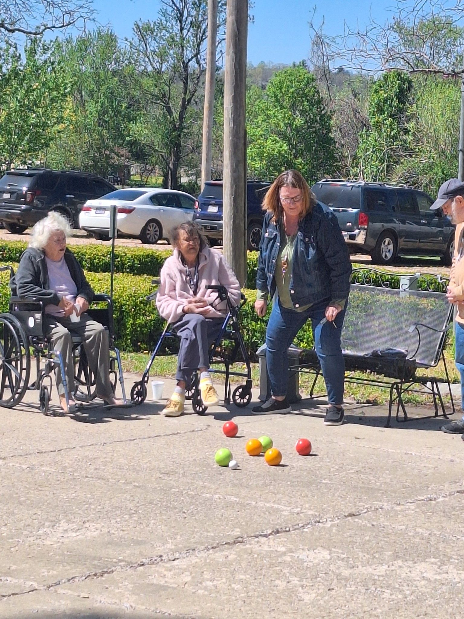 A group of people are playing bocce ball in a park.