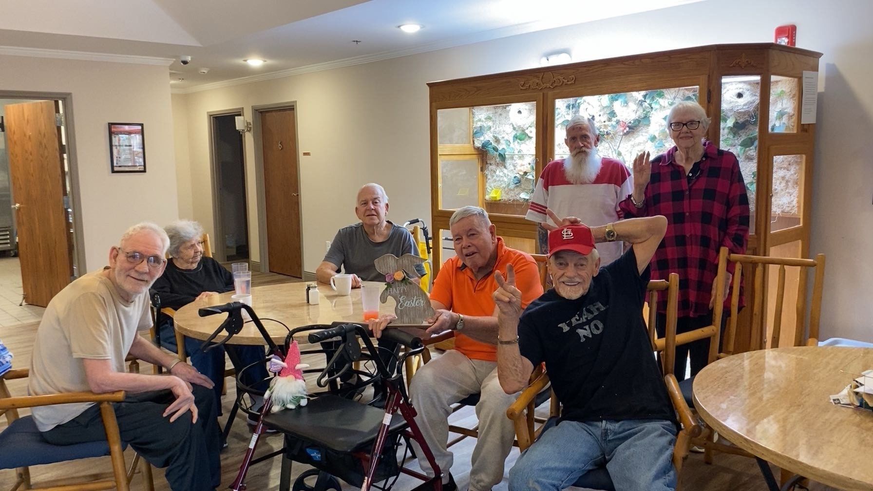 A group of elderly people are sitting at tables in a room.
