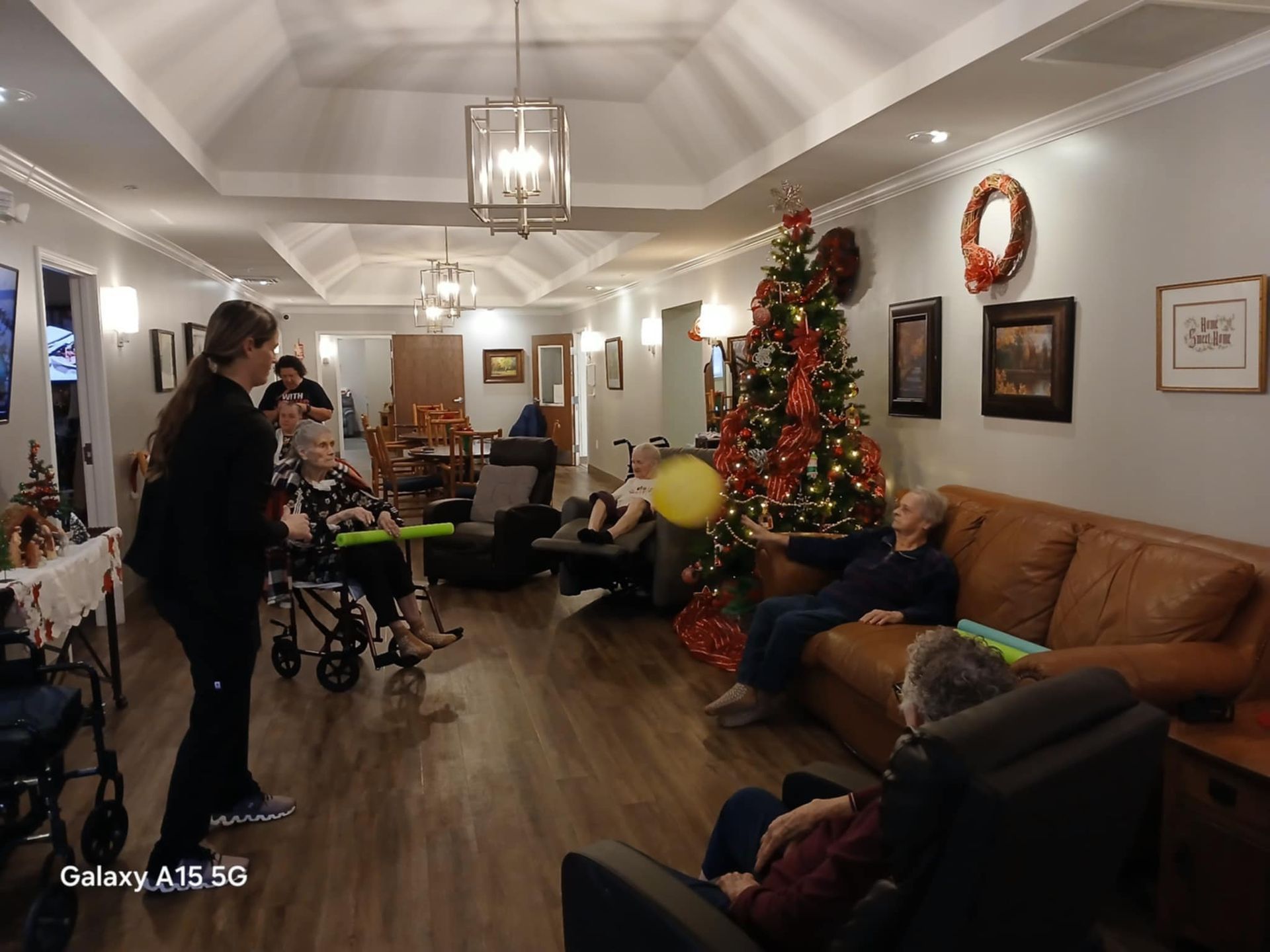 A group of people are sitting in a living room with a christmas tree.