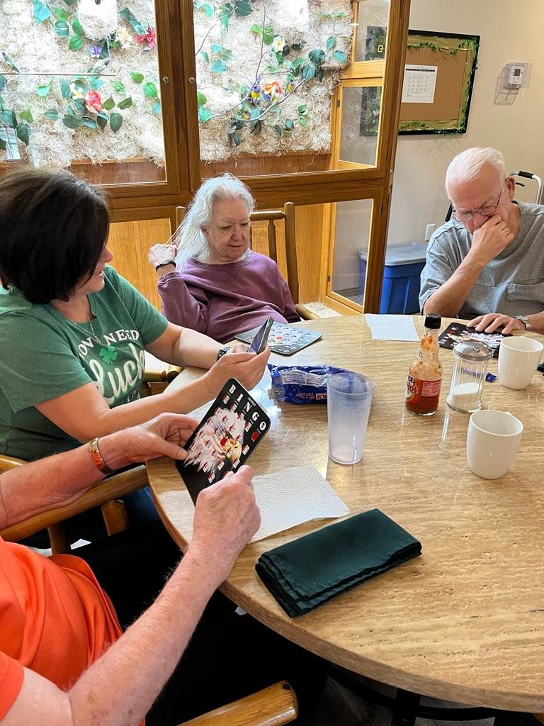 A group of elderly people are sitting around a table playing cards.