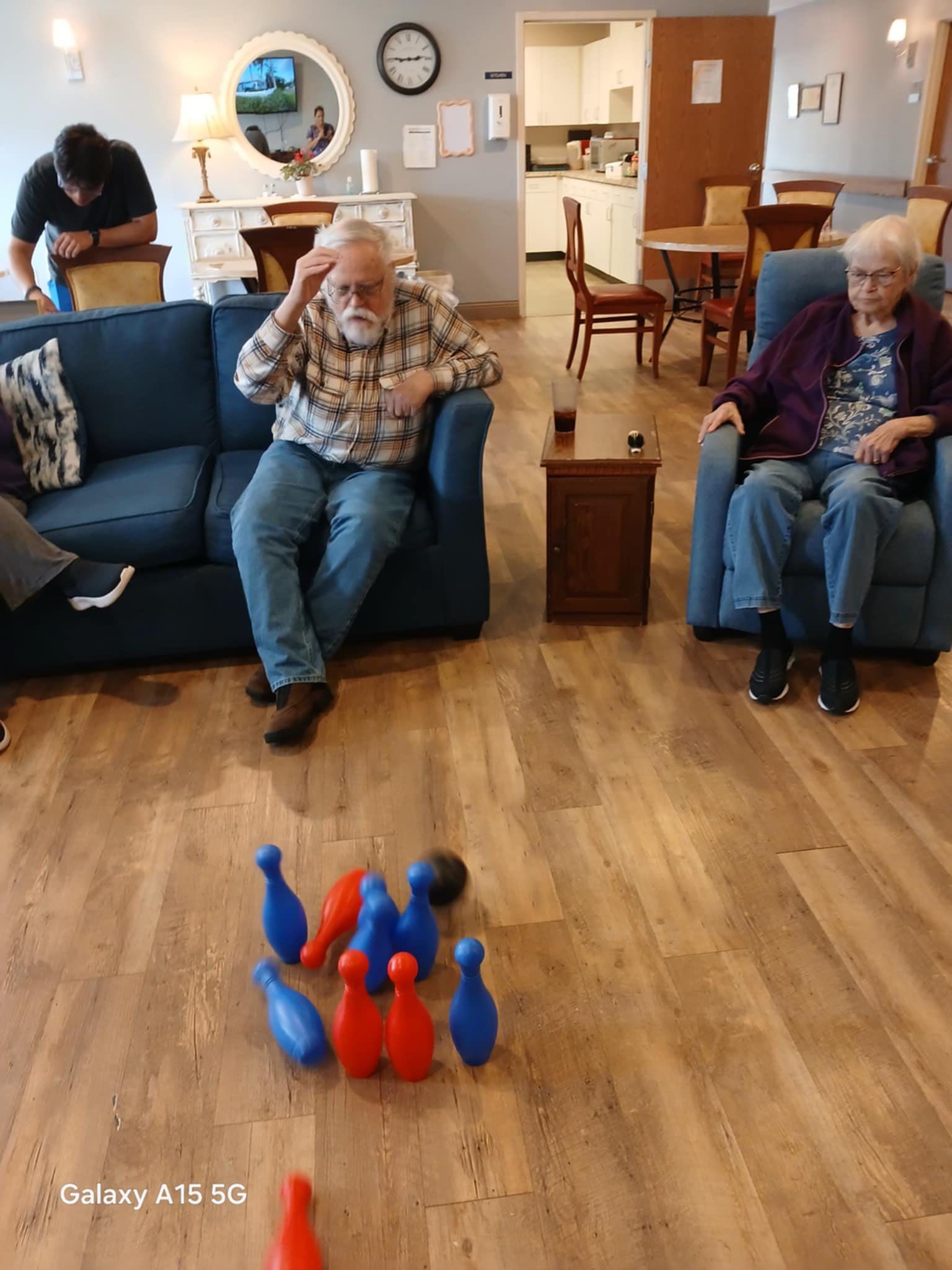 A group of elderly people are playing bowling in a living room.