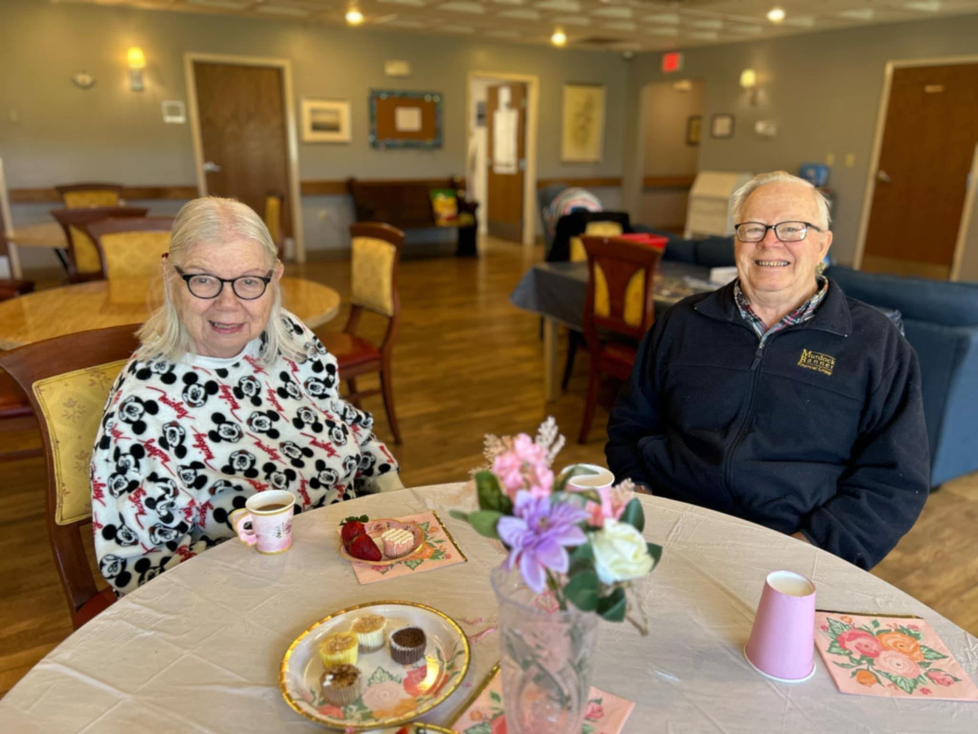 A man and a woman are sitting at a table with flowers.