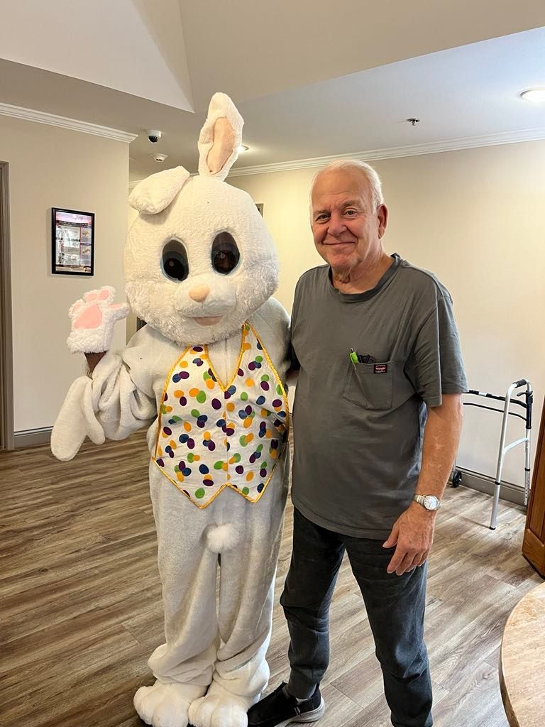A man is standing next to a stuffed bunny rabbit in a room.