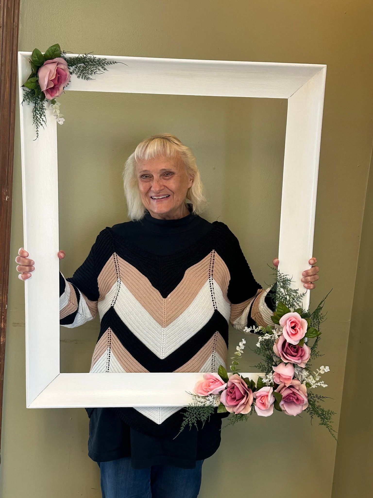 A woman is holding a picture frame with flowers on it.