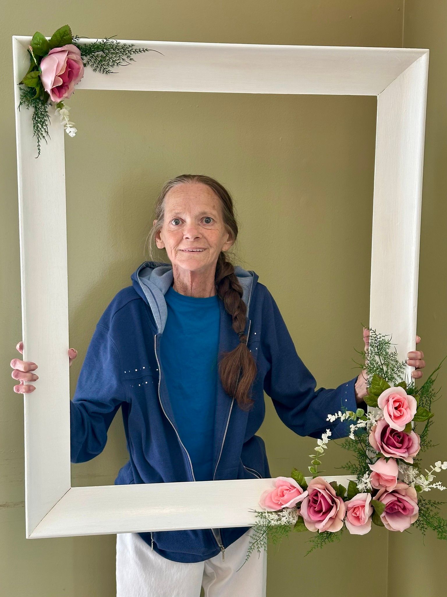 A woman is holding a picture frame with pink flowers on it.