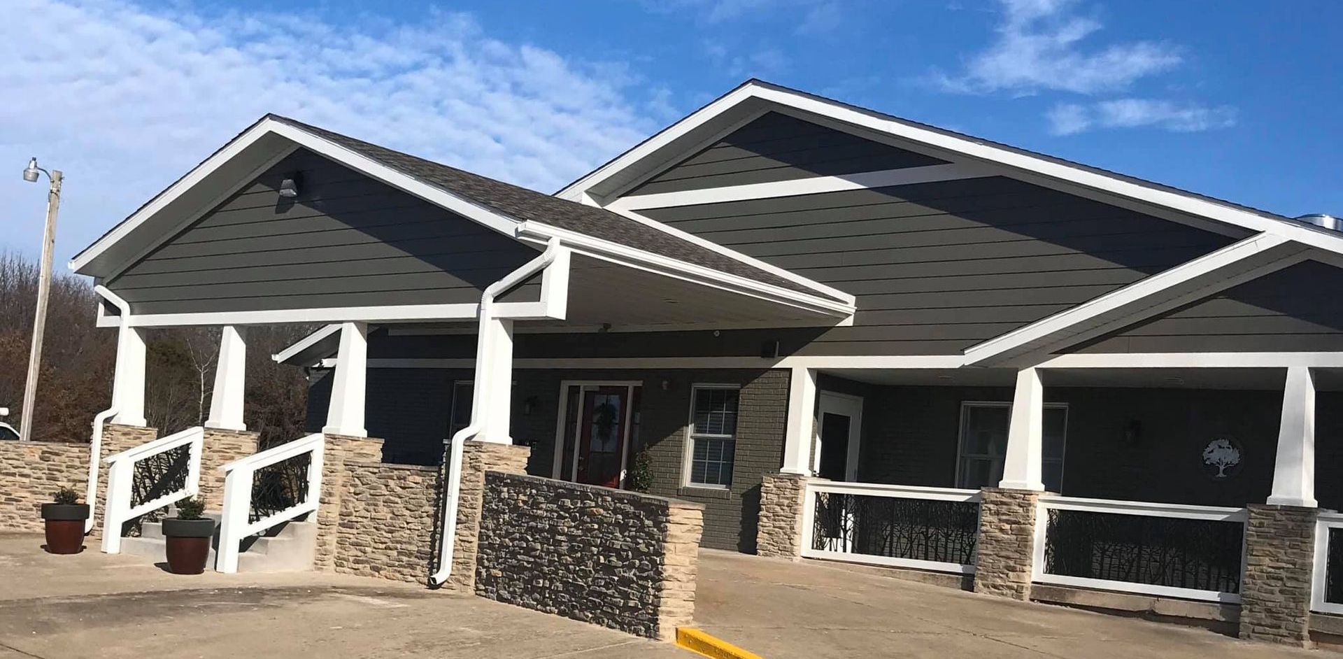 A large house with a porch and a blue sky in the background.