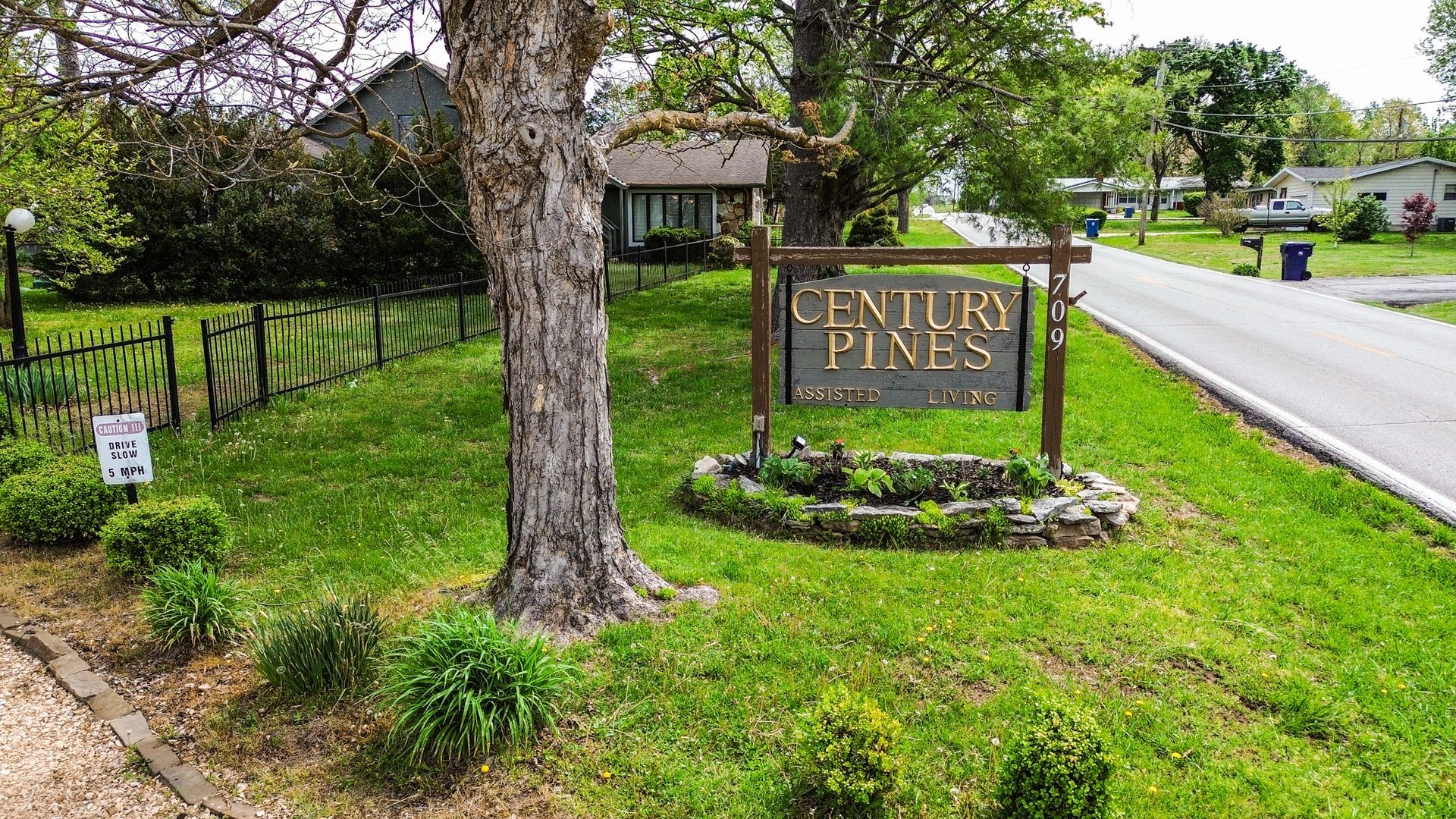 A sign for century pines is sitting in the middle of a lush green field.