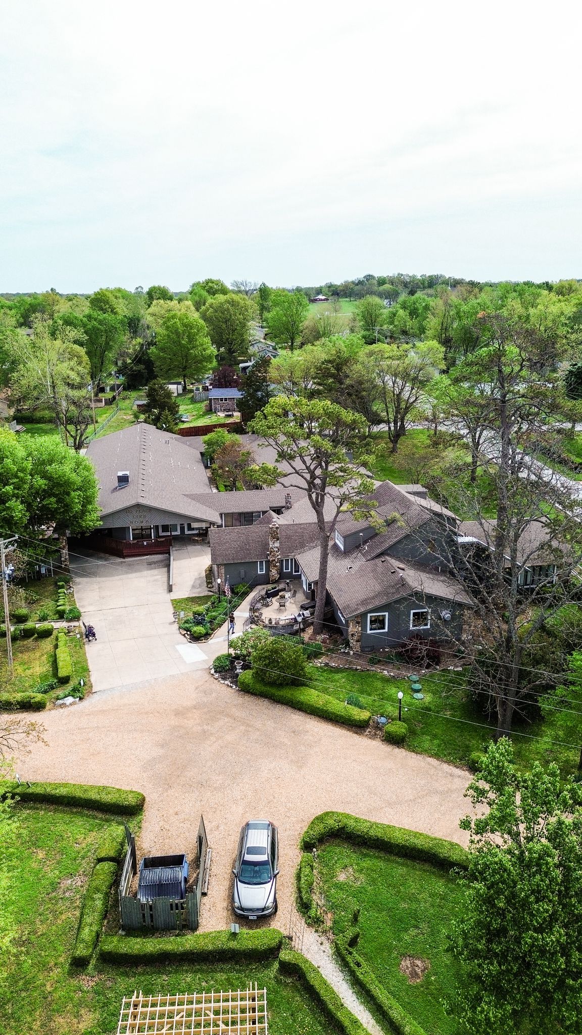An aerial view of a large house surrounded by trees and bushes.