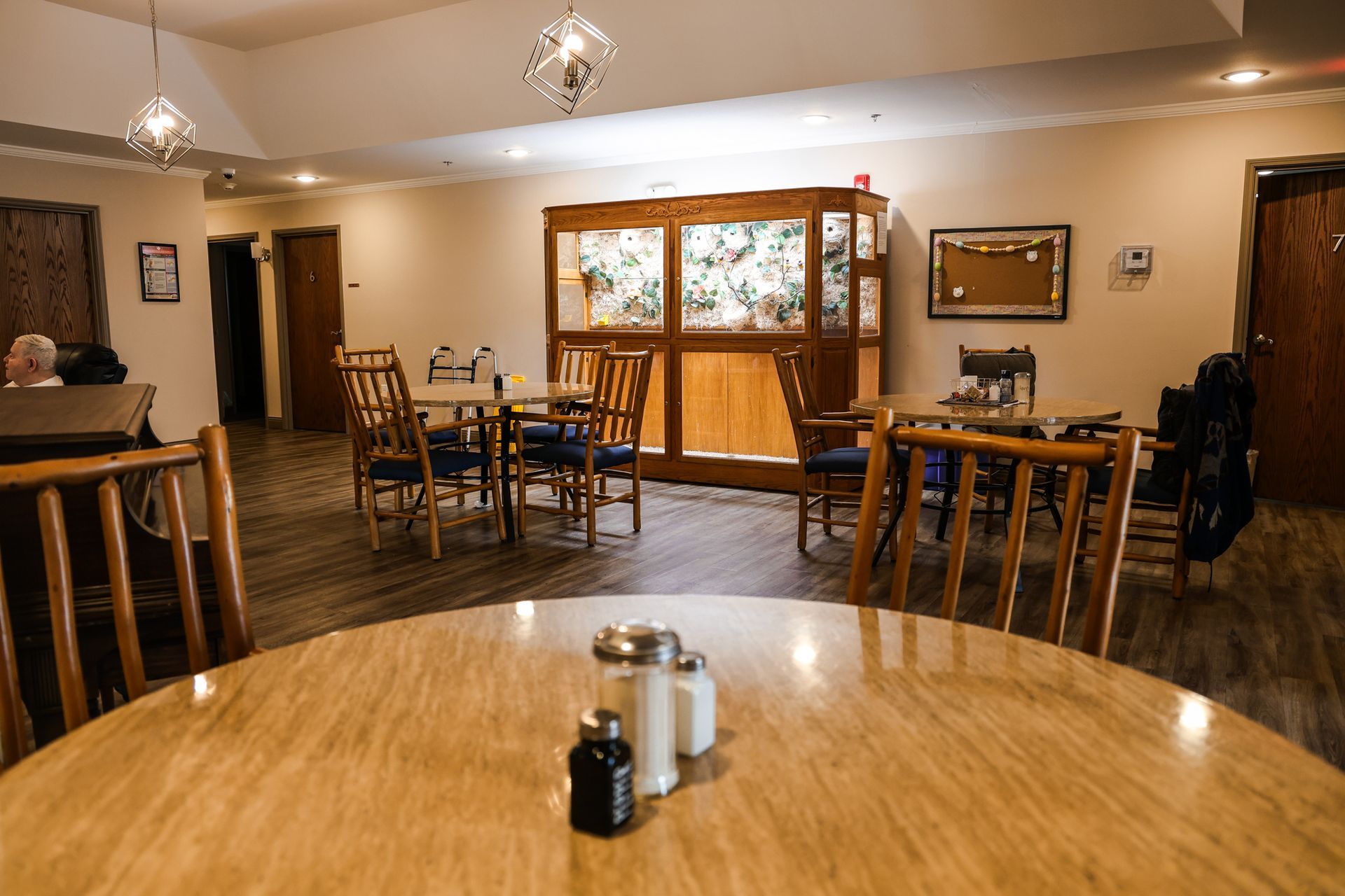 A restaurant with tables and chairs and a table with salt and pepper shakers on it.