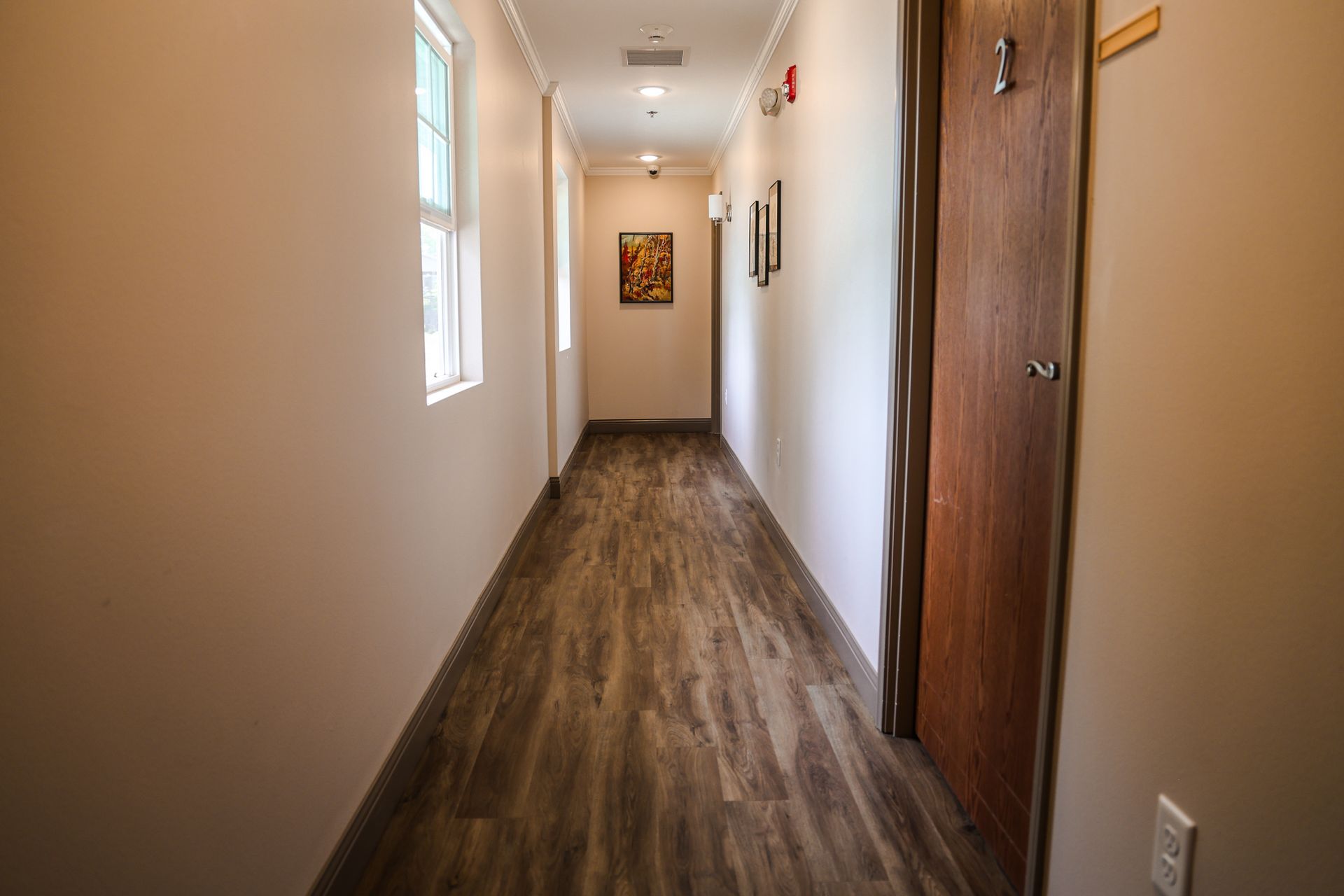A long hallway with wooden floors and a wooden door in a building.