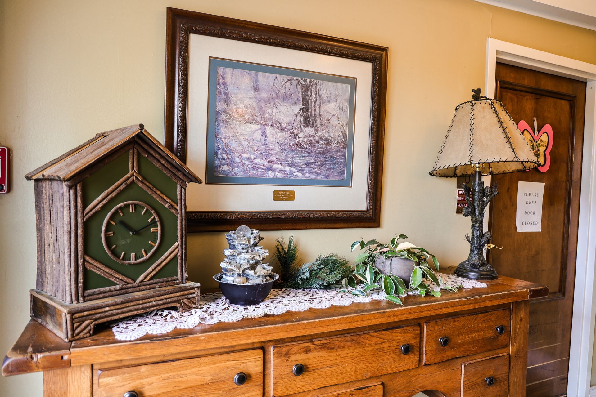 A wooden dresser with a clock and a lamp on it