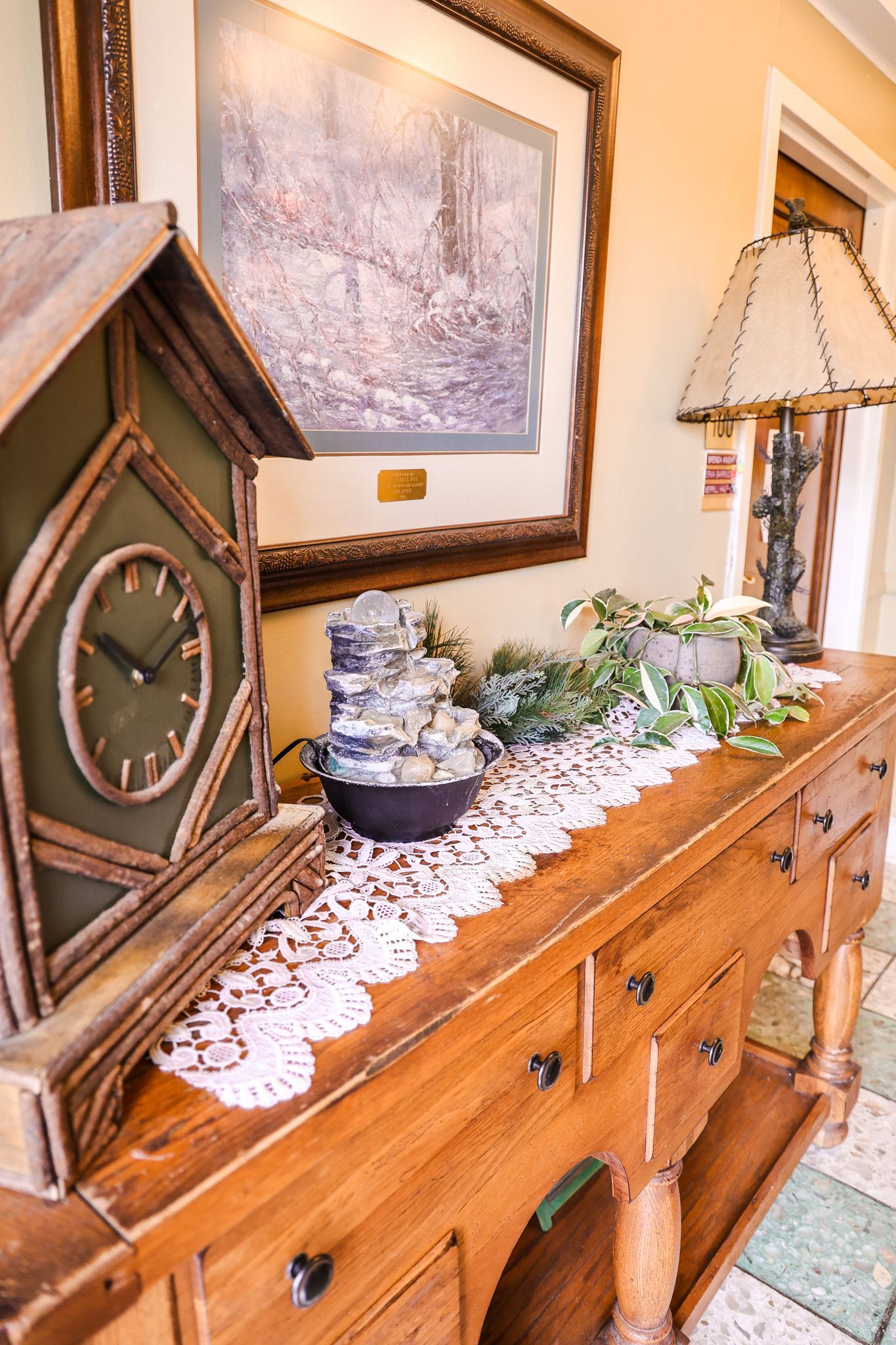 A wooden table with a clock and a lamp on it.