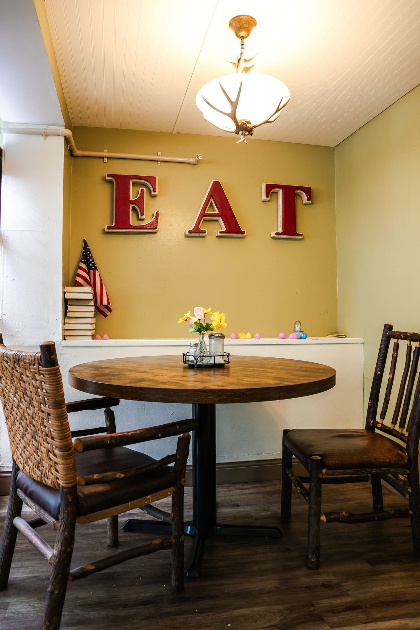 A wooden table and chairs in a room with the word eat on the wall.