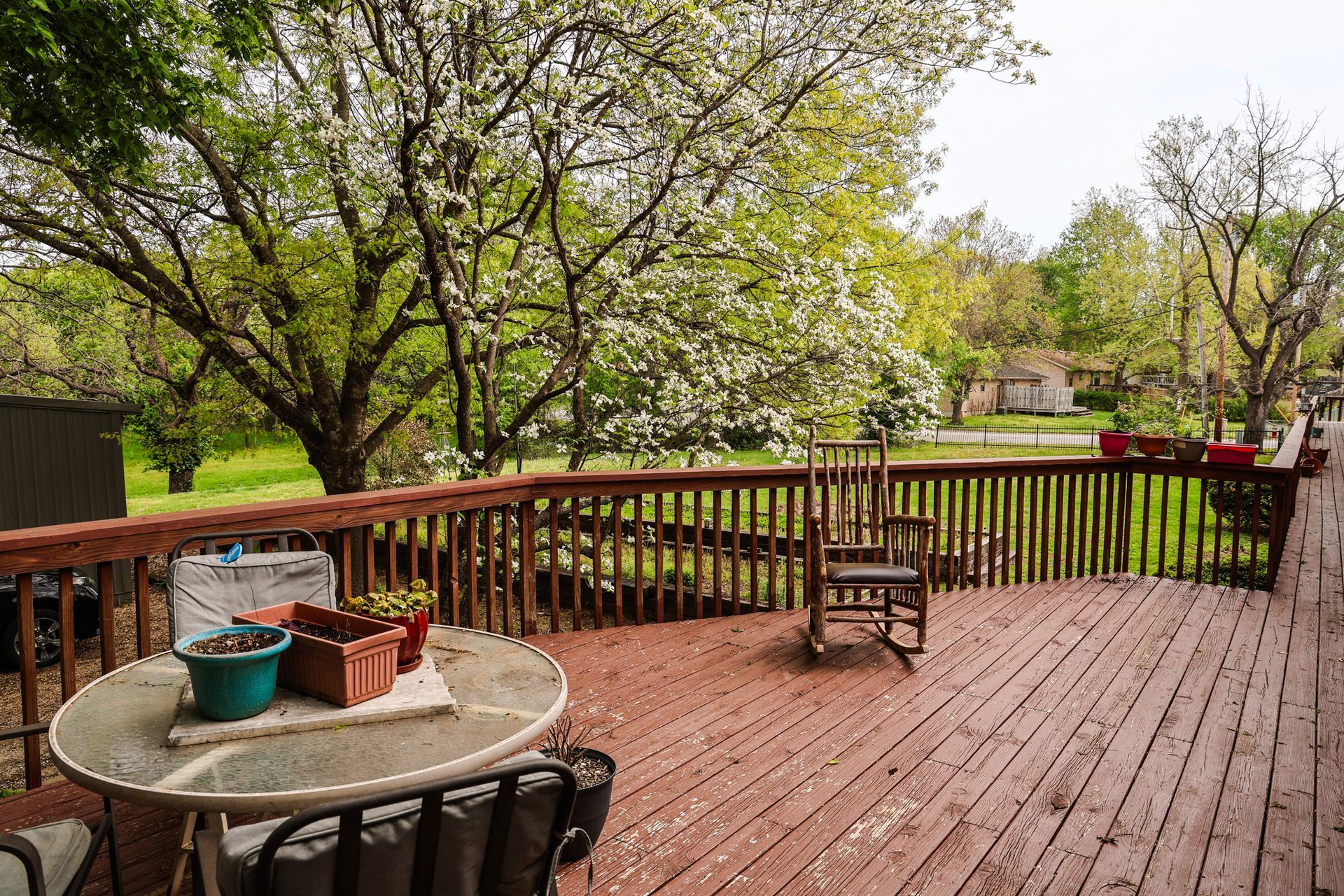 A wooden deck with a table and chairs and a rocking chair.