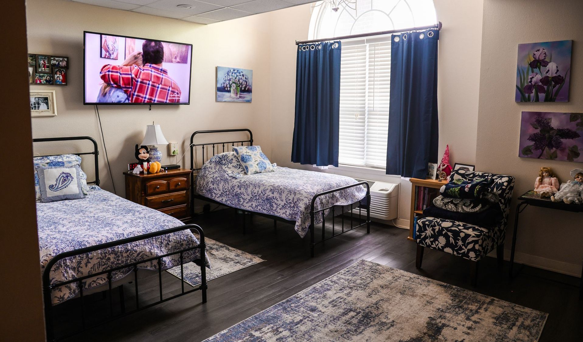 A bedroom with two beds and a television on the wall.