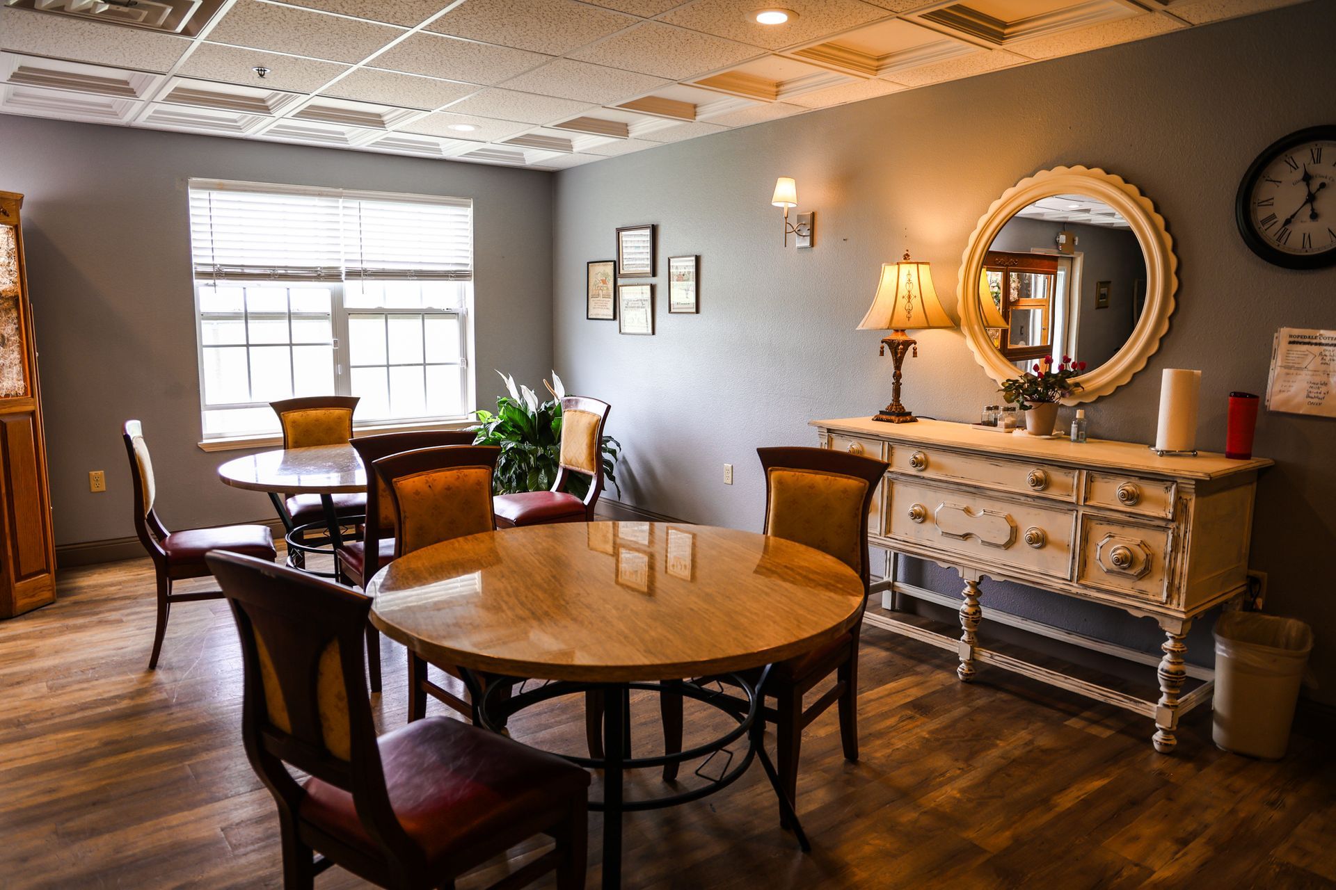 A dining room with a table and chairs and a clock on the wall.
